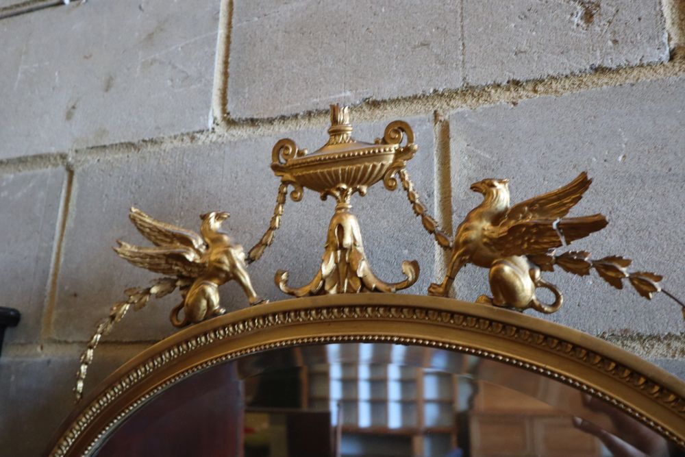 A late Victorian gilt oval wall mirror, surmounted by an urn, flanked by winged griffins, width 70cm height 75cm